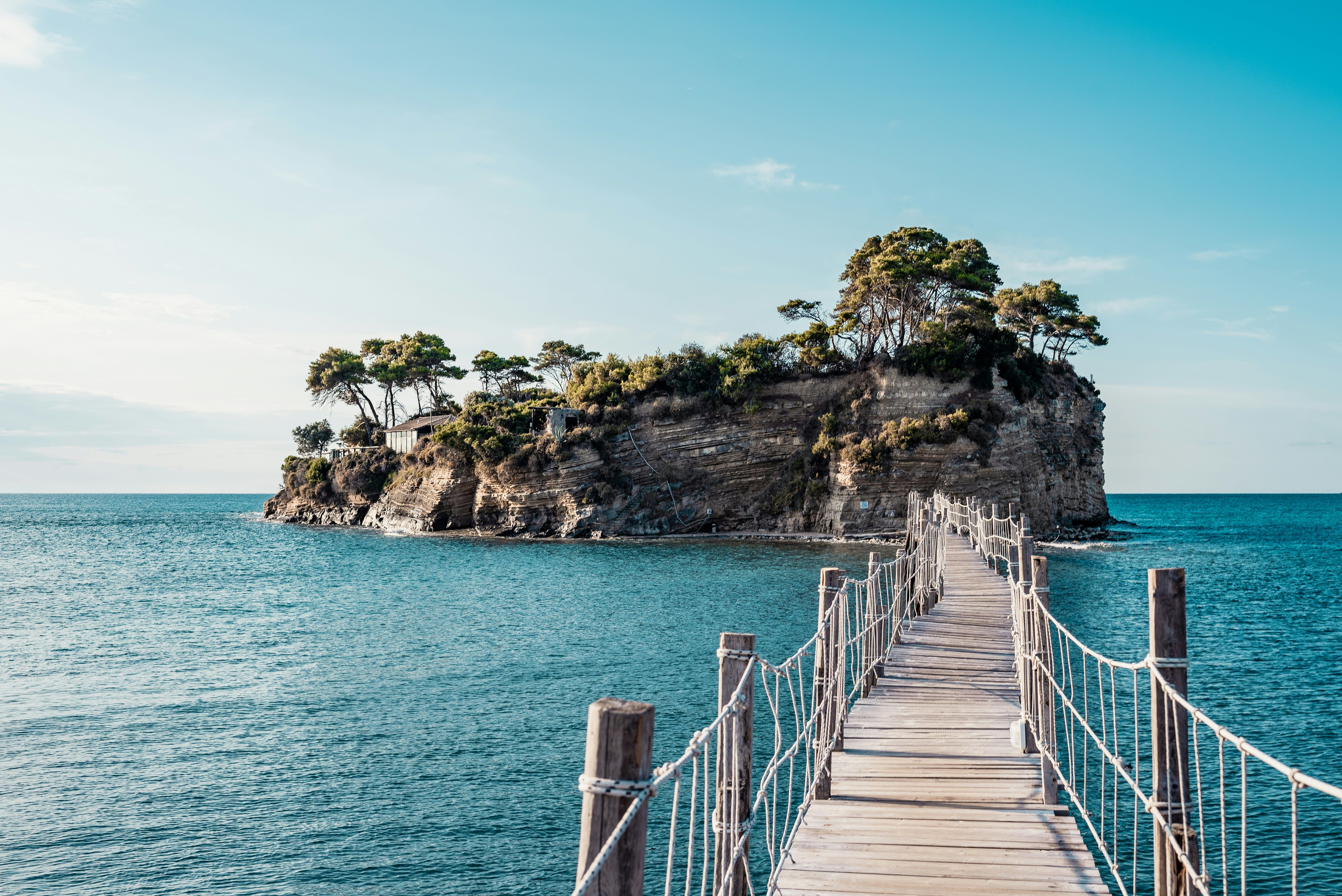 Pont en bois vers une île rocheuse aux eaux turquoise
